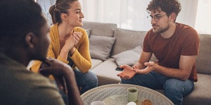 three friends sitting around a coffee table chatting